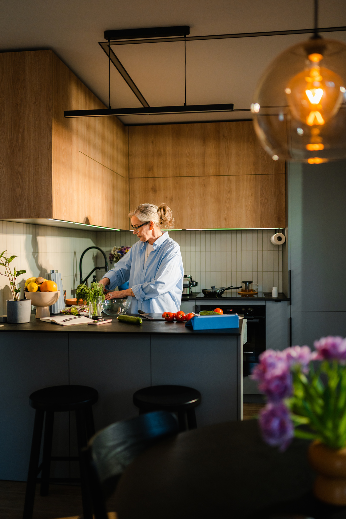 Man cooking in a modern kitchen with pendant lighting and fresh flowers on the counter