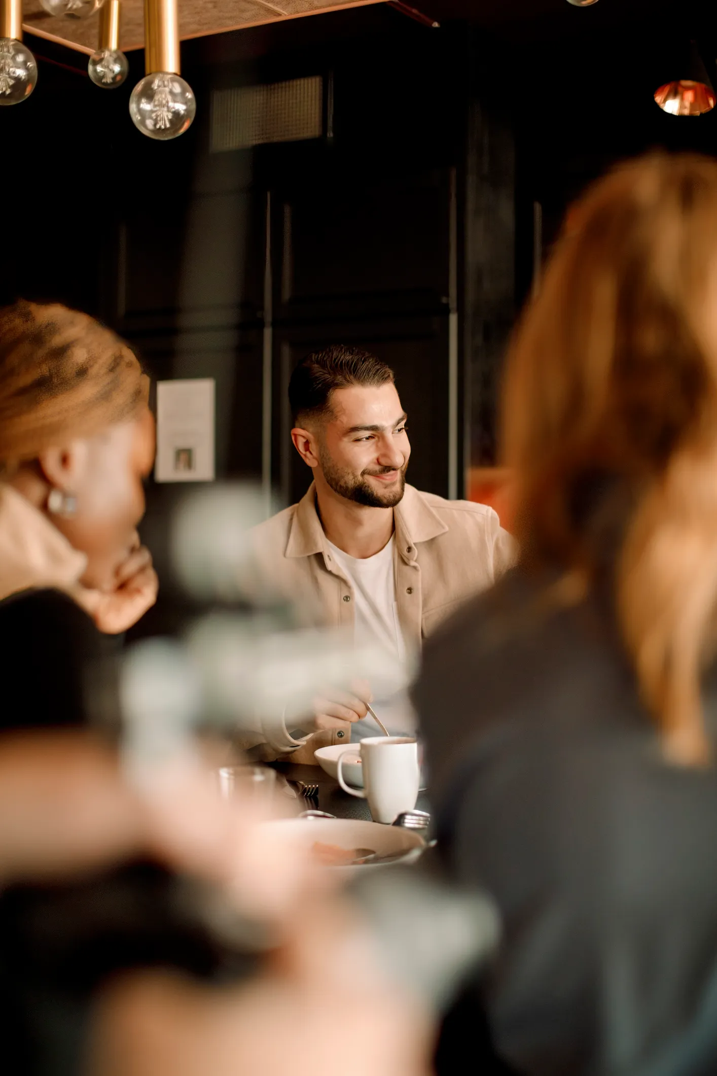 A man smiling while talking to colleagues in a modern office setting.