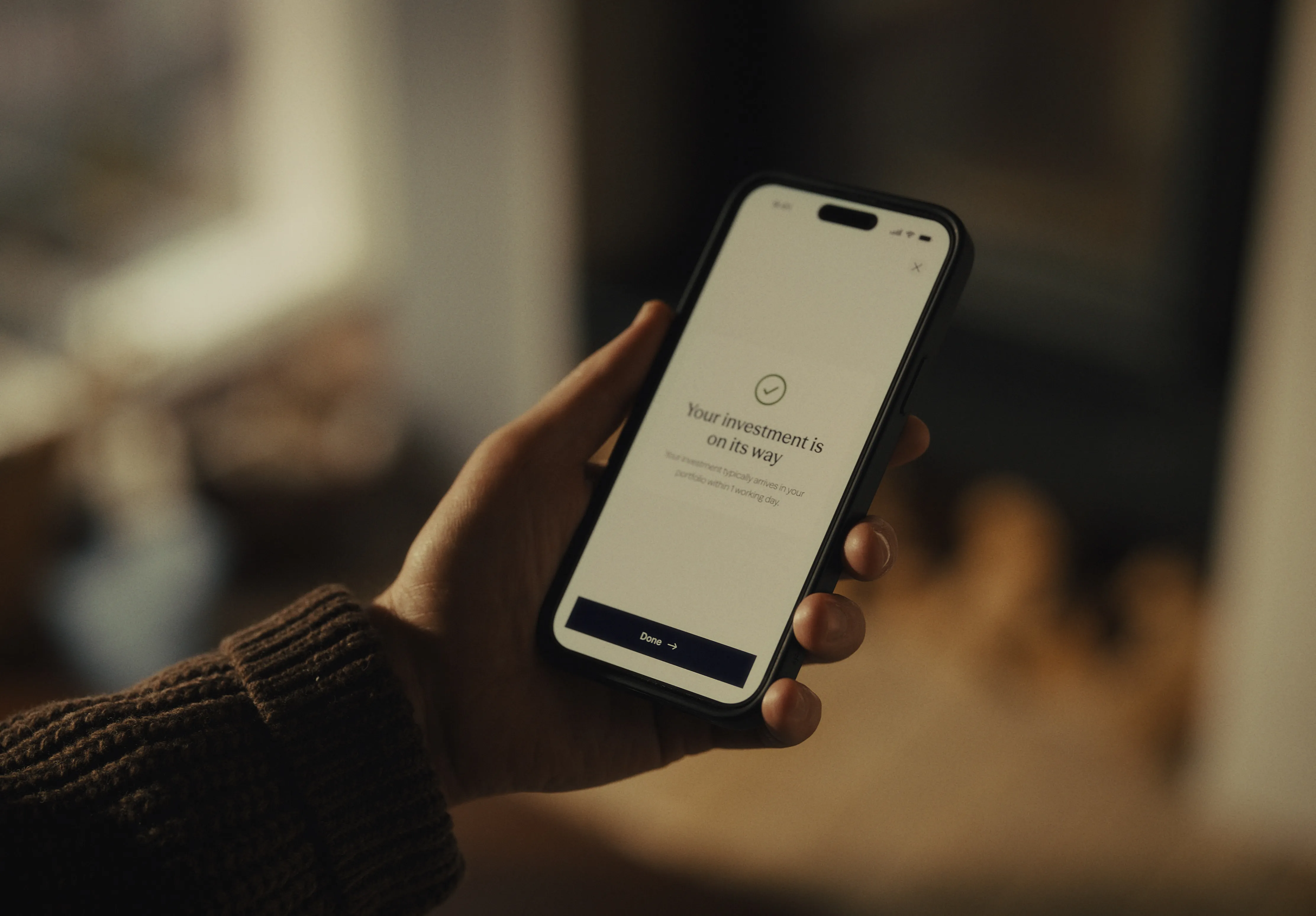 Hand holding a smartphone with the Sidekick app investment confirmation screen.